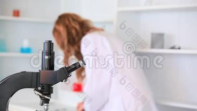 年轻女子透过显微镜看